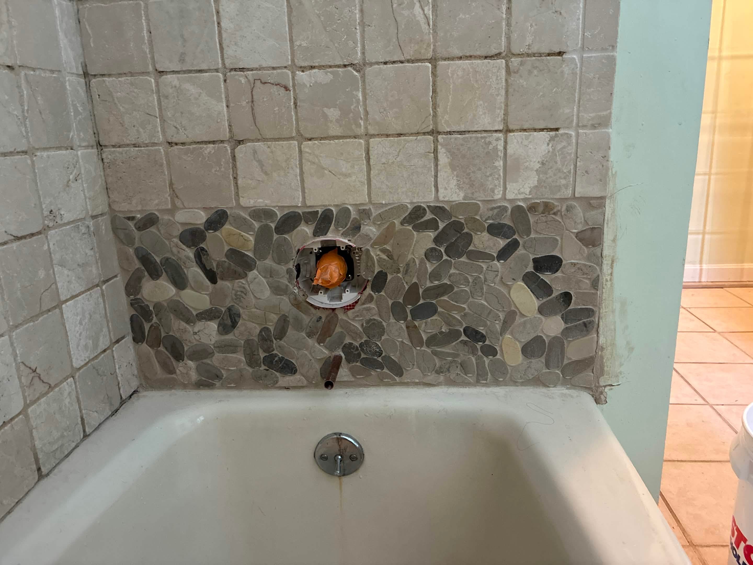 Finished grouted pebble mosaic accent band across tub surround