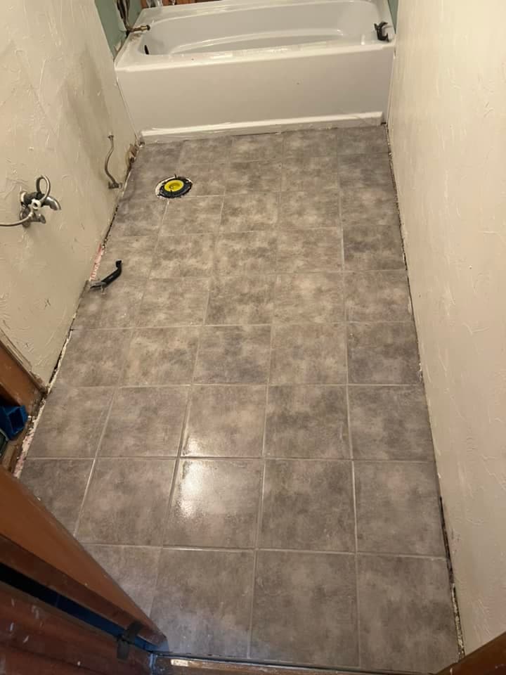 Bathroom tile floor install in progress with new tub and gray ceramic tile, Juneau Alaska